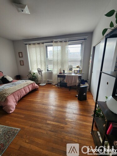 A bedroom with a bed, desk, and window.