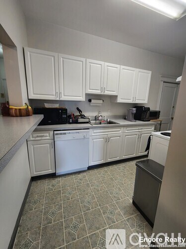 A kitchen with white cabinets and a black dishwasher.