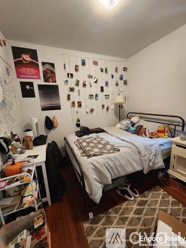 A bedroom with a bed, a desk, and a wall covered in posters and pictures.