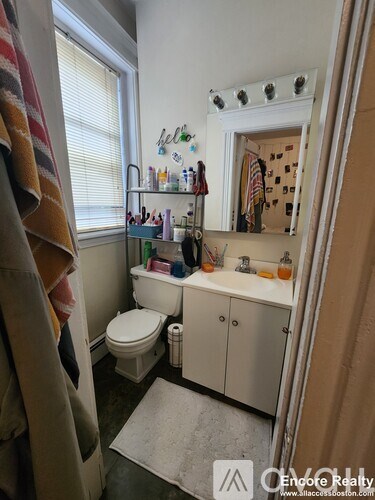 A bathroom with a toilet, sink, and a mirror.