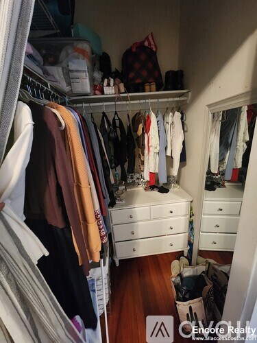 A closet with clothes hanging and a mirror on the wall.