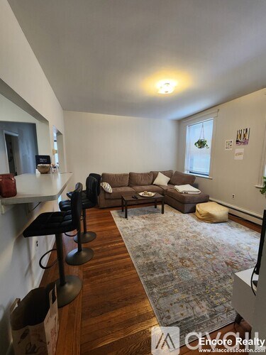 A living room with a couch, chairs, and a rug.