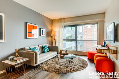 A living room with a grey couch, a coffee table, and a large window.