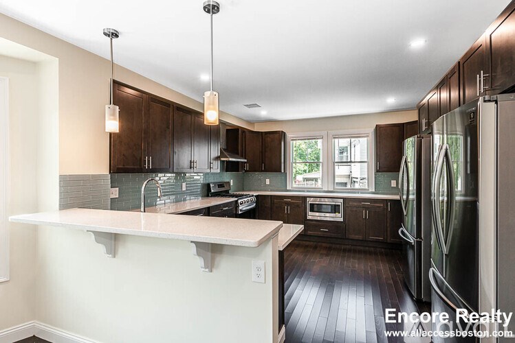 A modern kitchen with dark wood cabinets and stainless steel appliances.