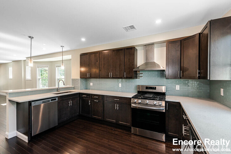A modern kitchen with dark wood cabinets and stainless steel appliances.