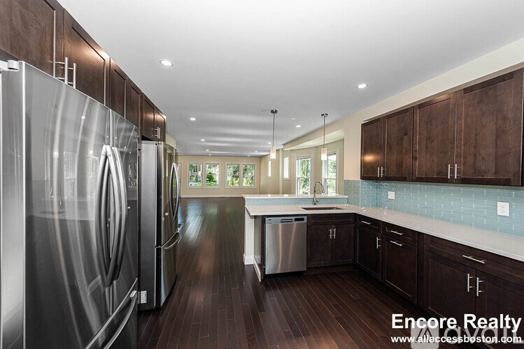 A modern kitchen with dark wood floors and stainless steel appliances.