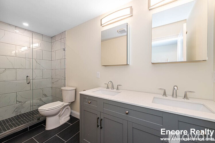 A bathroom with a toilet, sink, and mirror.