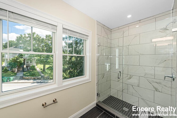 A bathroom with a walk-in shower and a window overlooking a garden.