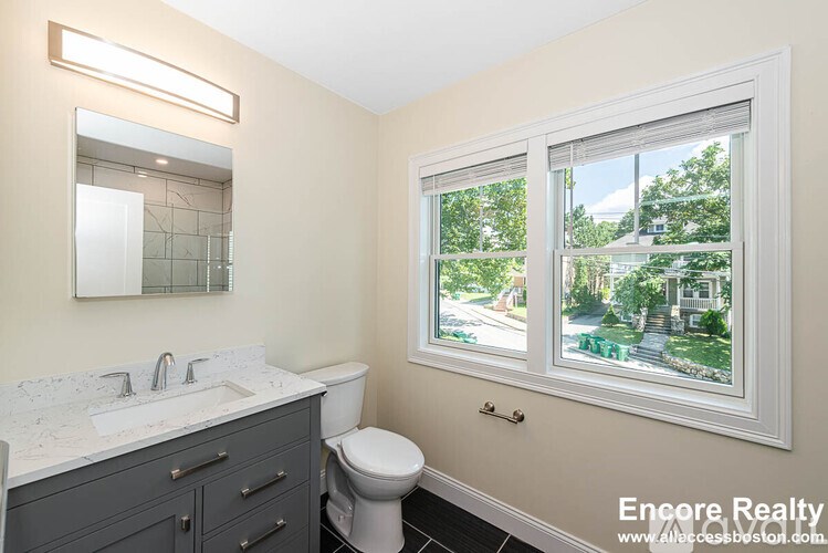 A bathroom with a toilet, sink, and window.