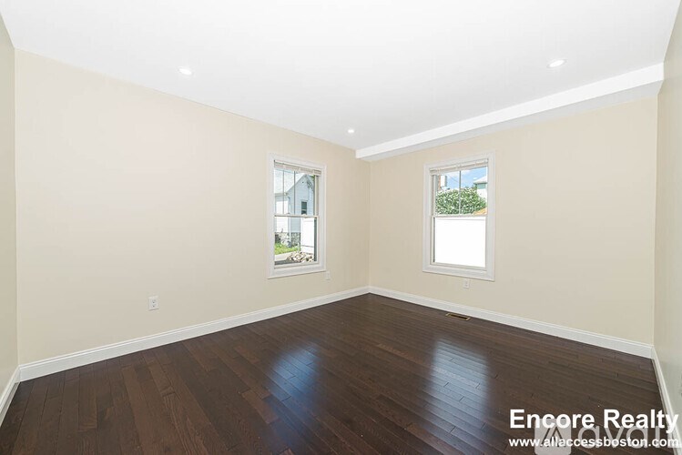 A room with wooden floors and two windows.