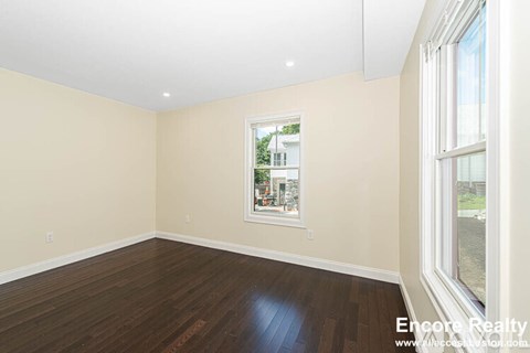 A room with a window and a wooden floor.