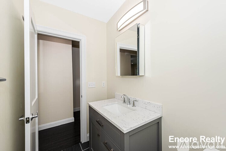 A bathroom with a sink, mirror, and a door.