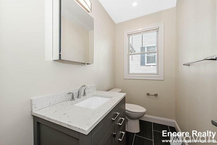 A bathroom with a sink, toilet, and a window.