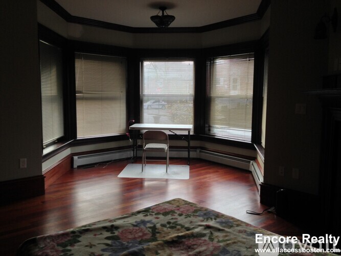 A room with a floral rug and a single chair.