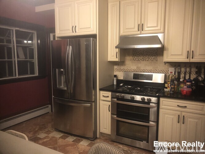 A kitchen with a stainless steel refrigerator and oven, and a black stove top.