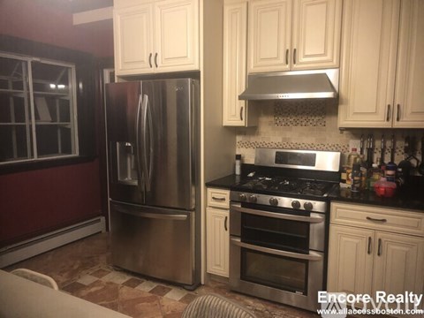 A kitchen with a stainless steel refrigerator and oven, and a black stove top.