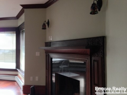 A fireplace in a room with a window and a wall hanging.