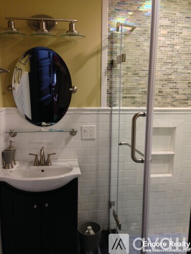 A bathroom with a sink, mirror, and shower.