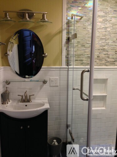 A bathroom with a sink, mirror, and shower.