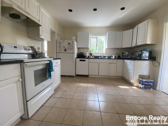 A kitchen with white appliances and cabinets.