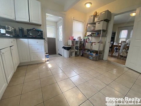 A kitchen with white cabinets and a tiled floor.