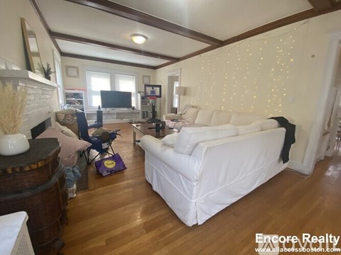 A living room with a white couch and wooden floors.