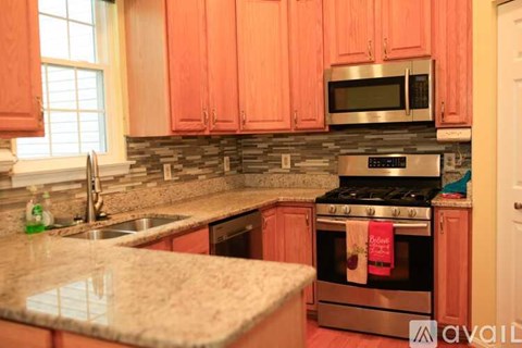 A kitchen with pink cabinets and a stone backsplash.