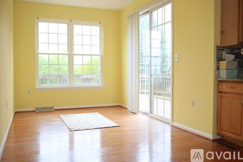 A room with yellow walls and a large window with a view of a fence and trees.