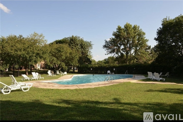 A pool surrounded by lawn chairs and trees.