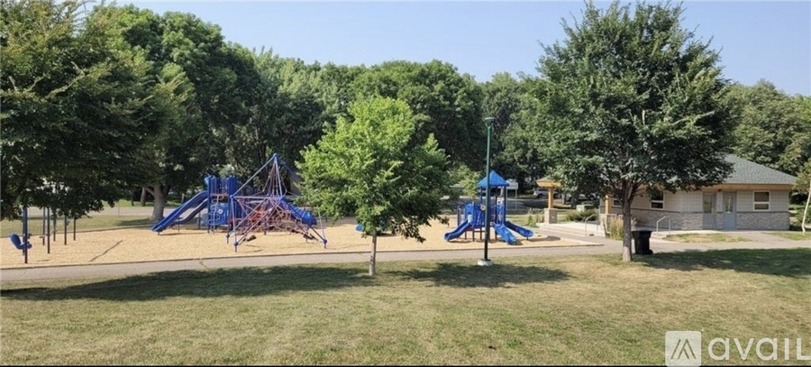 A playground with a blue swing set and a small building in the background.