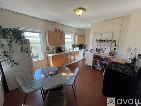 A kitchen with a table and chairs in the foreground and a potted plant on the left.