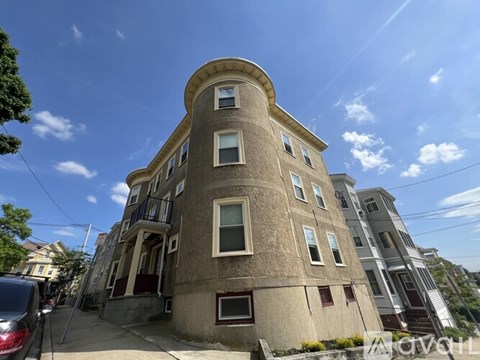 A tall building with a rounded top and multiple windows is seen under a clear sky.
