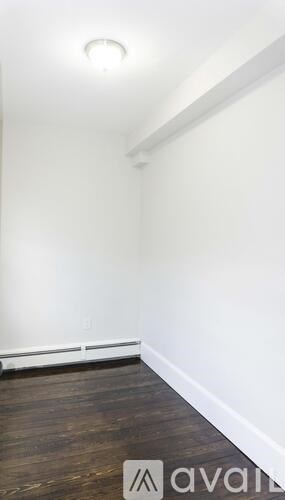 A room with a wooden floor and a white wall.