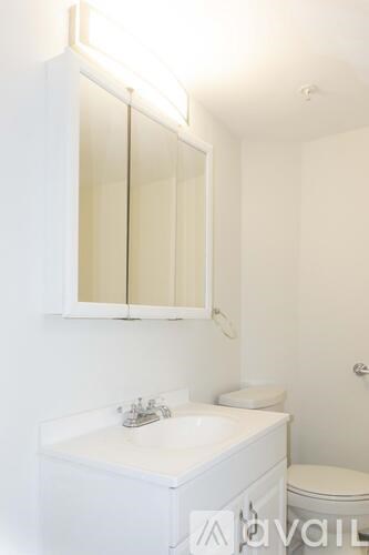 A white bathroom with a sink, mirror and toilet.
