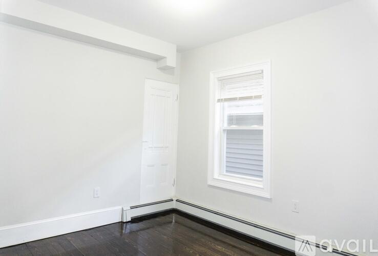A room with a white door and a window with blinds.