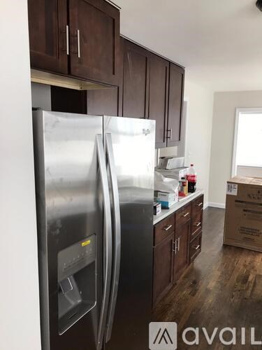 A stainless steel refrigerator in a kitchen with wooden cabinets.