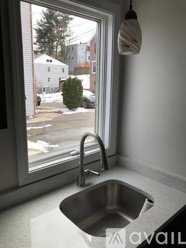 A kitchen sink with a window overlooking a snowy street.