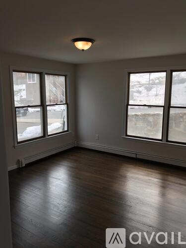 A room with wooden floors and a window overlooking a snowy street.
