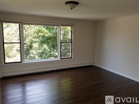 A room with wooden floors and a large window with a view of trees.