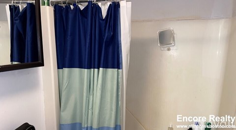 A shower curtain with blue and green stripes hanging in a bathroom.