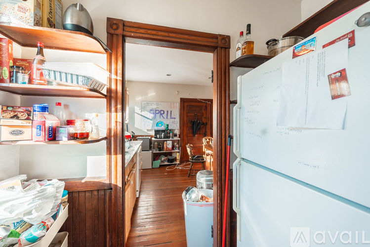 A kitchen with a white fridge and wooden floors.