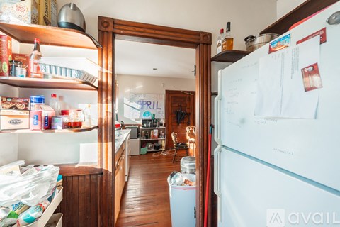 A kitchen with a white fridge and wooden floors.