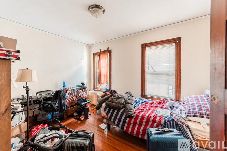 A room with a bed, suitcases, and clothes scattered around.