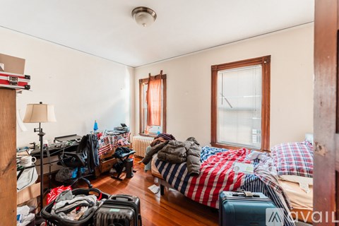 A room with a bed, suitcases, and clothes scattered around.