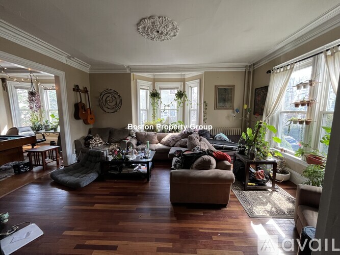 A living room with a piano and a guitar hanging on the wall.