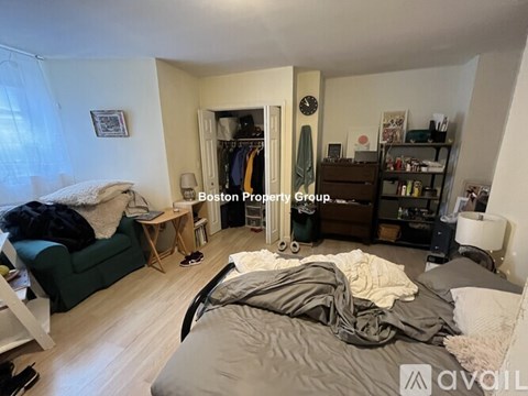 A bedroom with a bed in the center and a closet to the right.