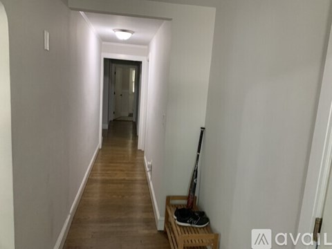 A long hallway with a wooden floor and white walls.