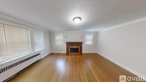 A spacious room with wooden floors and a fireplace.
