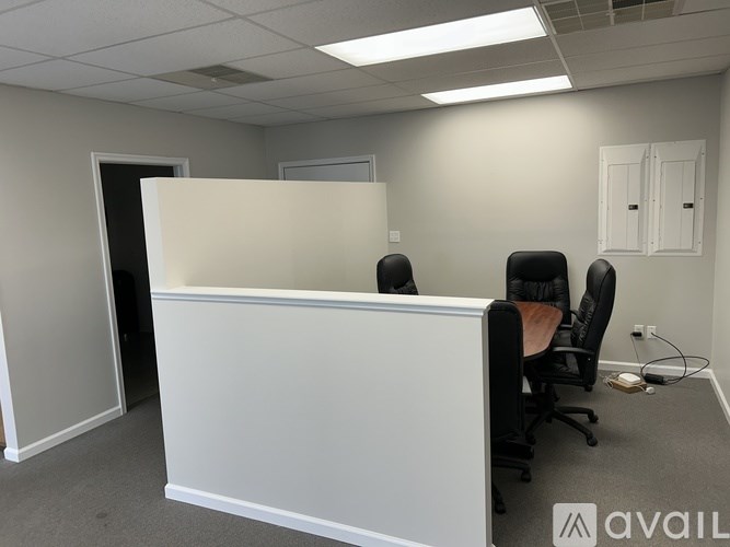 A white reception desk with two chairs in front of it.
