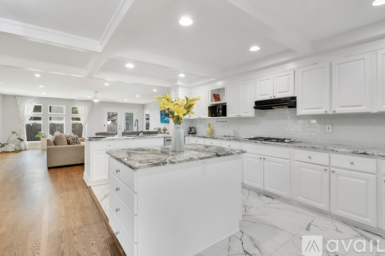 A kitchen with white cabinets and a marble countertop.